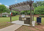 Thumbnail 15 of 20 - A wooden pergola is over a stone and concrete fireplace.