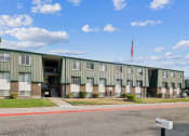 Thumbnail 30 of 35 - a green apartment building with an flag in front