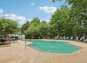 Thumbnail 13 of 20 - A pool surrounded by trees and chairs.