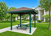 Thumbnail 2 of 12 - A green picnic table is in the middle of a grassy area.