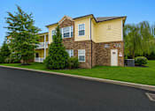 Thumbnail 3 of 23 - A two-story apartment building with a yellow and brown exterior.