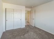 Thumbnail 17 of 34 - a bedroom with white doors and carpeting and a door to a hallway