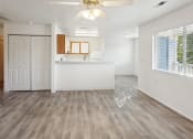 Thumbnail 7 of 34 - an empty living room with a kitchen and a ceiling fan