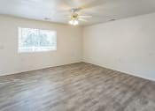 Thumbnail 9 of 34 - an empty living room with a window and a ceiling fan