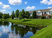 Thumbnail 6 of 16 - A serene lakeside view with a house and ducks.