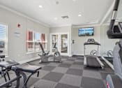 Thumbnail 27 of 36 - A gym with a variety of equipment including treadmills, stationary bikes, and weight machines.