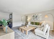 Thumbnail 1 of 28 - A living room with a white couch, a wooden coffee table, and a blue rug.