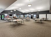 Thumbnail 19 of 22 - A large room with tables and chairs and a carpeted floor.