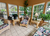 Thumbnail 13 of 22 - A sunroom with a couch, chair, and table.