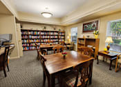Thumbnail 11 of 22 - A room with a long table surrounded by chairs and a bookshelf filled with books.