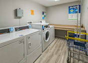 Thumbnail 7 of 22 - A laundromat with washers and dryers and a shopping cart.