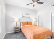 Thumbnail 11 of 30 - a bedroom with an orange bed and a ceiling fan