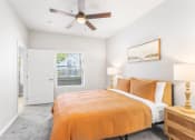 Thumbnail 9 of 30 - a bedroom with an orange bed and a ceiling fan