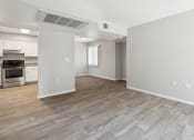 Thumbnail 8 of 56 - the living room and kitchen of an apartment with white walls and wood flooring at Vista Linda, Santa Fe, 87507
