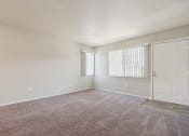 Thumbnail 21 of 56 - an empty living room with carpet and a white door at Vista Linda, Santa Fe, NM 87507
