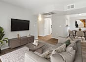 Thumbnail 1 of 58 - A living room with a grey couch, a coffee table, and a flat screen TV mounted on the wall.
