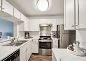 Thumbnail 6 of 24 - A modern kitchen with white cabinets and stainless steel appliances.