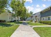 Thumbnail 3 of 16 - a sidewalk between two rows of houses with grass and trees