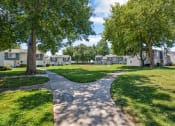 Thumbnail 13 of 16 - a pathway through a park with green grass and trees