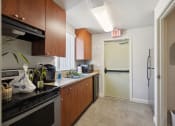 Thumbnail 7 of 16 - a kitchen with a refrigerator and sink and an exit door