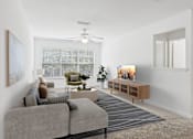 Thumbnail 2 of 20 - A living room with a grey sofa, a green armchair, a coffee table, and a television.