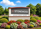 Thumbnail 1 of 16 - A sign for Stonewood Apartment Homes is surrounded by flowers.