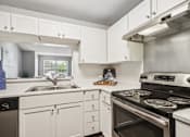 Thumbnail 7 of 24 - A modern kitchen with white cabinets and stainless steel appliances.