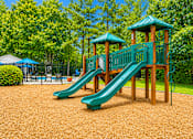 Thumbnail 5 of 9 - A playground with a green slide and wooden structure.
