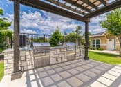 Thumbnail 14 of 26 - a patio with an outdoor kitchen and a pergola