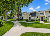 Thumbnail 3 of 9 - A row of houses with a sidewalk and greenery.