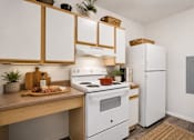 Thumbnail 20 of 24 - A kitchen with white appliances and wooden cabinets.