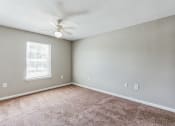 Thumbnail 11 of 26 - an empty living room with carpet and a ceiling fan
