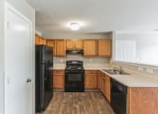 Thumbnail 7 of 26 - an empty kitchen with wooden cabinets and black appliances