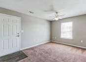 Thumbnail 5 of 26 - an empty living room with a white door and a ceiling fan