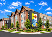 Thumbnail 1 of 16 - A modern building with a large mural on the side.