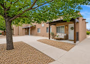 Thumbnail 9 of 24 - A tree is in front of a building with a white door and windows.