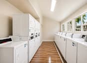 Thumbnail 9 of 9 - A laundry room with washers and dryers.