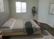 Thumbnail 3 of 16 - A bedroom with a bed, a small plant, and a painting on the wall.