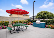 Thumbnail 2 of 8 - A red umbrella is on a green picnic table.