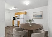 Thumbnail 5 of 9 - A kitchen with a refrigerator, a dining table with chairs, and a painting on the wall. at Diamond Fork Apartments, Spanish Fork, Utah