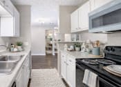 Thumbnail 10 of 17 - A kitchen with white cabinets and a black stove top. at Parkland at Orange Park Apartments , Orange Park