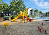 Thumbnail 4 of 12 - A playground with a yellow slide and red monkey bars.