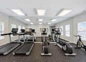 Thumbnail 2 of 8 - A spacious gym with treadmills, exercise bikes, and other equipment.