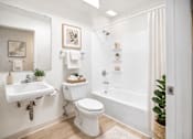 Thumbnail 7 of 8 - A white bathroom with a toilet, sink, and bathtub.