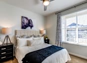 Thumbnail 7 of 25 - A bedroom with a large bed, a ceiling fan, and a painting of a bison head on the wall.