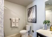 Thumbnail 10 of 25 - A white toilet sits in a bathroom next to a white sink.