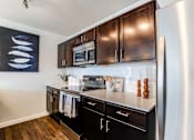 Thumbnail 5 of 25 - A kitchen with black cabinets and stainless steel appliances.