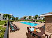 Thumbnail 4 of 18 - Outdoor swimming pool with lounge chairs and umbrellas at Cypress Court Apartments, St Cloud, 56303
