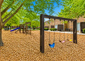 Thumbnail 6 of 13 - Playground area with swings and wood chip surface at Stratford Arms Apartments, Riverdale, GA