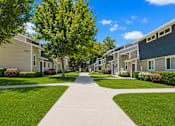 Thumbnail 4 of 9 - A tree-lined walkway leads to apartment buildings.